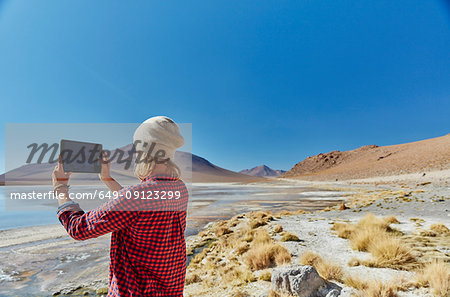 Woman photographing landscape, using digital tablet, Salar de Chalviri, Chalviri, Oruro, Bolivia, South America