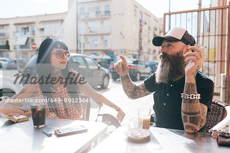 Mature hipster couple chatting at sidewalk cafe, Valencia, Spain