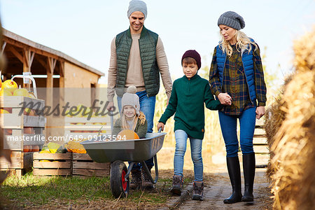 Couple with son and daughter in wheelbarrow at pumpkin patch