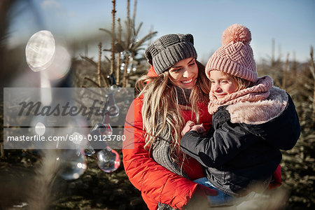 Girl and mother looking at forest christmas tree lights