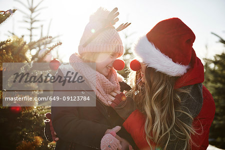 Girl and mother in christmas tree forest wearing red noses