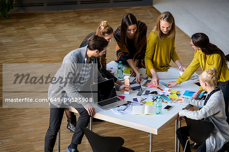 Team of male and female designers discussing colour swatches on design studio table