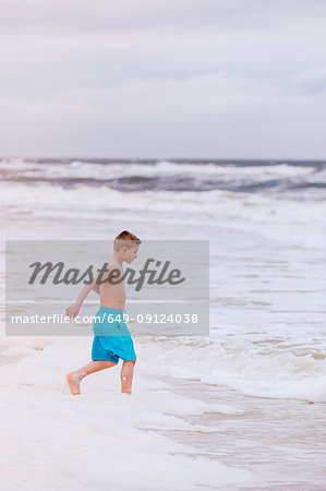 Boy running into sea, Dauphin Island, Alabama, USA