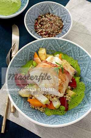 Cod wrapped in bacon on a bed of vegetables and couscous with green sauce