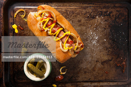 A hot dog with ketchup, mustard and fried onions served on a vintage baking tray