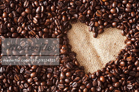 Lots of coffee beans revealing hessian fabric bag underneath