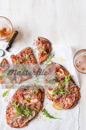 Quick pita bread pizza with sliced tomatoes, prosciutto, mozzarella and fresh rocket