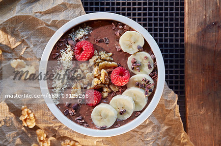 A smoothie bowl with chocolate, banana, raspberries and walnuts