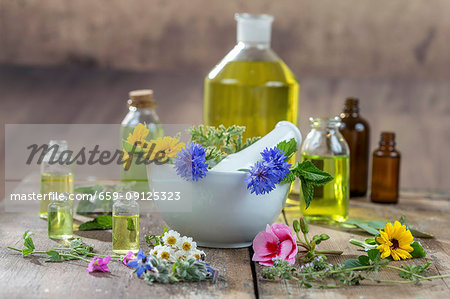 Various healing flowers, herbs and oils in and around a mortar