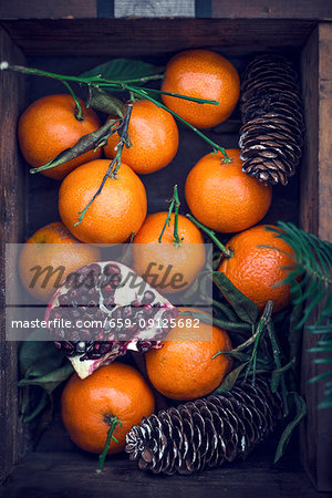 Mandarins and pomegranates in a wooden crate