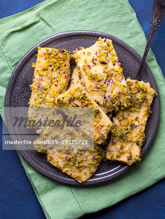 Baked polenta cheese bars topped with pistachio nuts and Parmesan