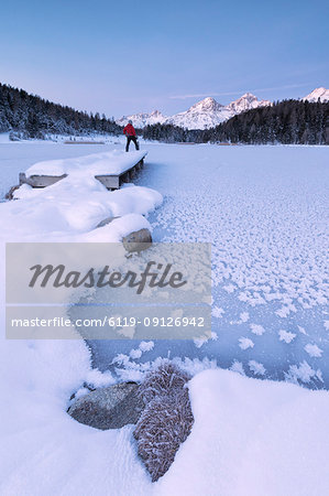 Man standing on the shore of frozen lake, Lej da Staz, St. Moritz, Engadine, Canton of Graubunden (Grisons), Switzerland, Europe