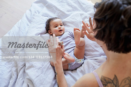 Baby girl lying on bed, mother looking over her, playing