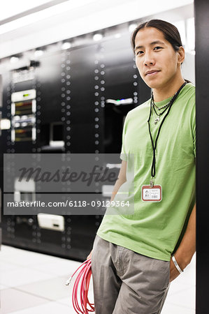Portrait of an Asian American computer technician in a large computer server room