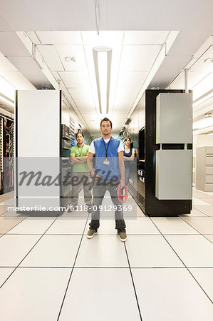 Portrait of three multi-ethnic technicians who work in a large computer server room.