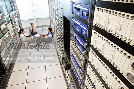 Three multi-ethnic technicians working in a large computer server room.