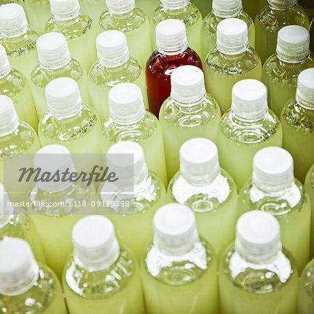 Closeup of bottles with lemon flavoured water on a bottling plant production line.  With one red bottle used as a marker.