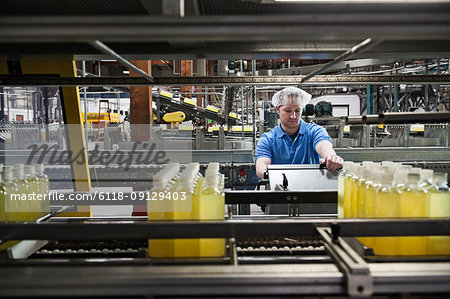 Caucasian male employee working in a bottling plant while wearing a head net.