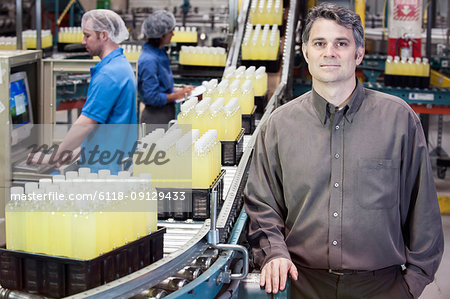 Portrait of a Caucasian male management person next to a conveyor belt in a bottling plant for lemon flavoured bottled water.