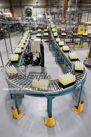 Conveyor belt full of lemon flavoured bottled water in a bottling plant.