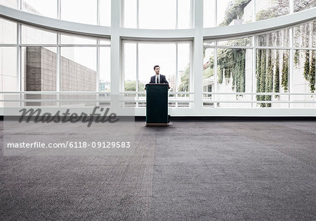 Businessman  at a podium with no one to talk to.