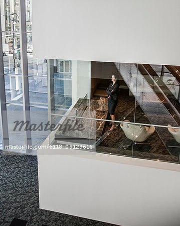 Businesswoman standing in a conference room window in a large business centre.