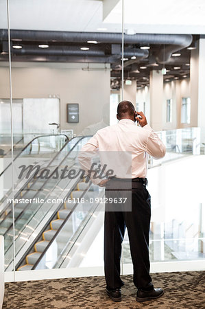 Black businessman on the phone in a large business centre lobby.