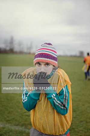 Caucasian woman blowing on her hands to stay warm at a sporting event in the winter.