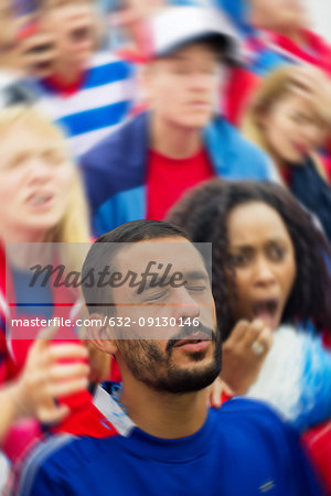 Sports enthusiasts looking upset during sports match