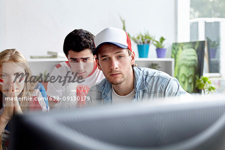 Sports enthusiasts watching match on TV at home