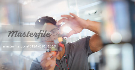 Focused, innovative male entrepreneur examining prototype Focused, innovative male entrepreneur examining prototype