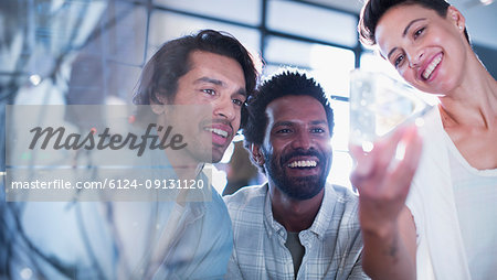 Smiling, curious, innovative entrepreneurs examining glass triangle prototype