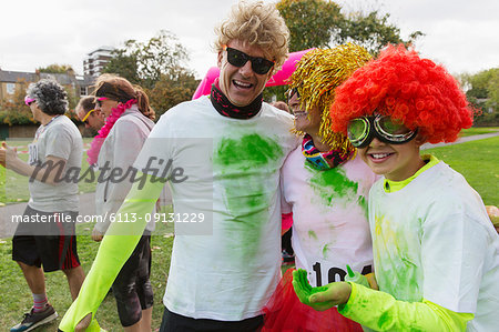 Portrait playful runners in wigs and holi powder at charity run in park