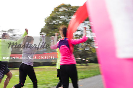 Enthusiastic family runners crossing finish line at charity run in park