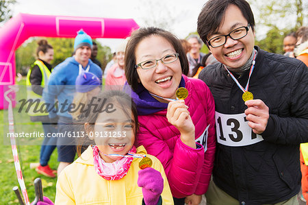 Portrait enthusiastic family runners showing medals at charity run