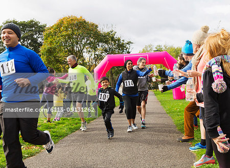 Runners reaching for water, running at charity run in park