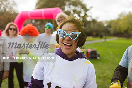 Portrait playful female runner in silly sunglasses at charity run in park