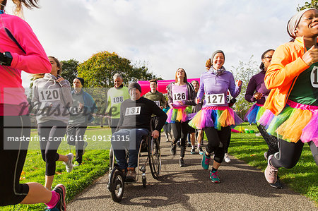 Man in wheelchair among runners at charity race in park