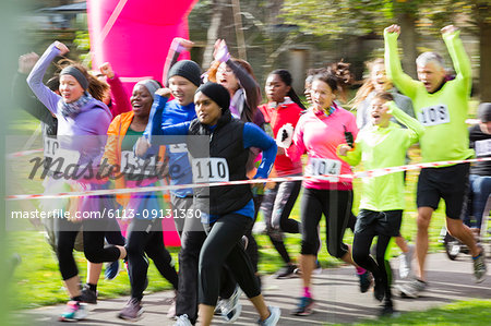 Enthusiastic runners cheering and running at charity run in park