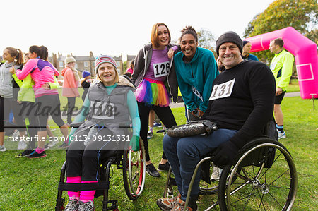 Portrait smiling friends in wheelchairs at charity race in park