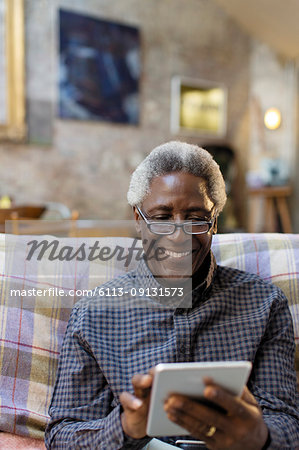 Smiling senior man using digital tablet on sofa