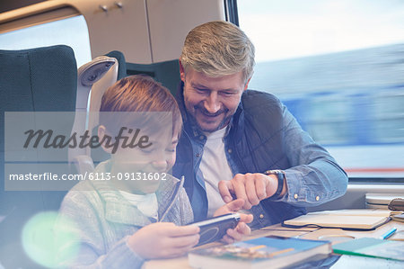 Father and son using smart phone on passenger train