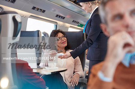 Woman with credit card using contactless payment, paying attendant on passenger train