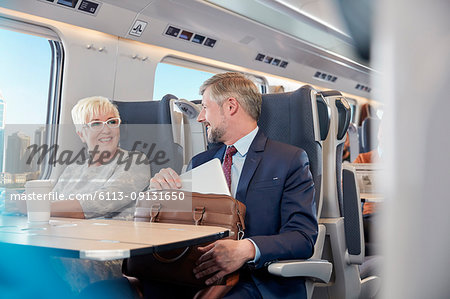 Businessman and businesswoman working, talking on passenger train