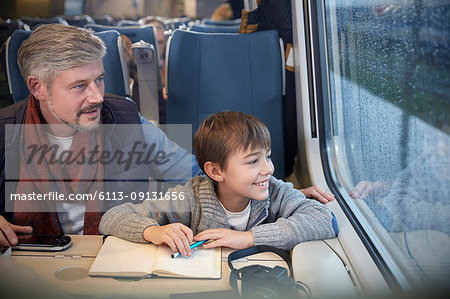Father and son looking out window on passenger train