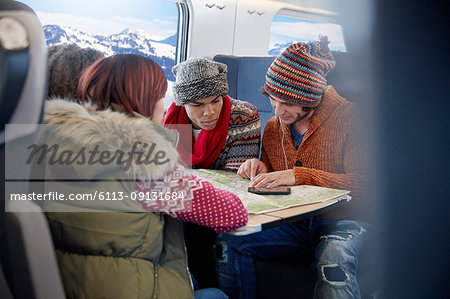 Young friends with map planning on passenger train