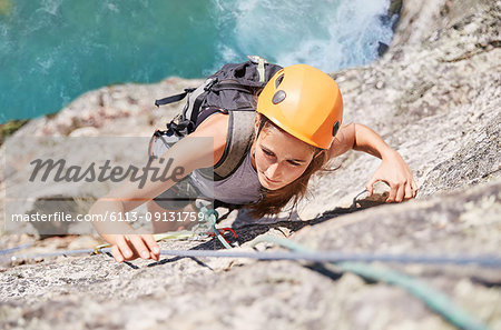 Focused, determined female rock climber scaling rock