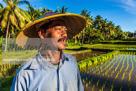 Portrait of Balinese farmer standing next to a rice field in Ubud District in Gianyar, Bali, Indonesia