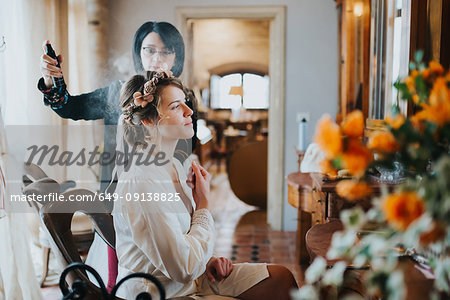 Bride preparing for wedding with hairstylist