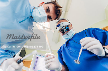 Dentist and dental nurse treating patient, personal persepctive